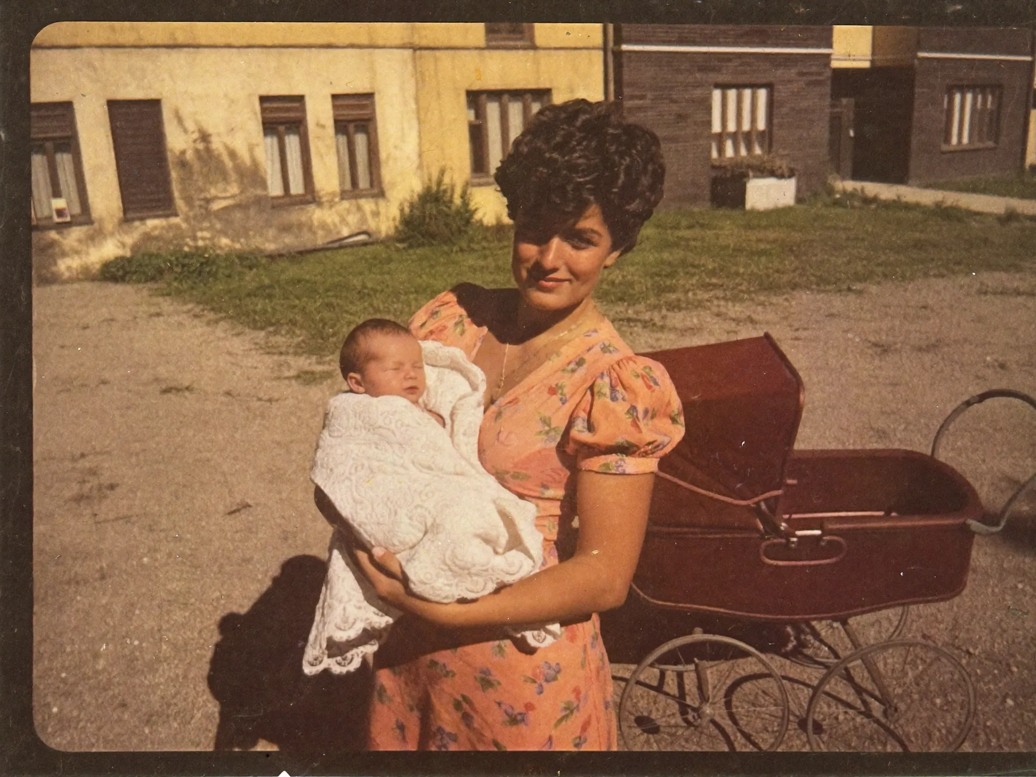 Fotografie z konce sedmdesátých let — mladá maminka s miminkem u kočárku
